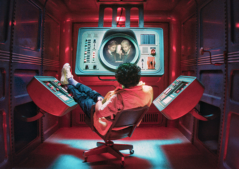Szenenbild: Rasputin Rumpus (in der Mitte des Bildes) sitzt in einem abgeschlossen Raum. Er beobachtet auf dem Monitor, was die Kinder machen.